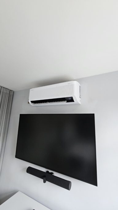 Wall-mounted air conditioning unit installed above a television